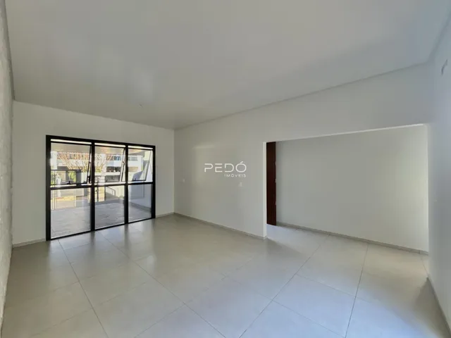 Ambiente interno de uma sala ampla com piso de cerâmica e portas de vidro.