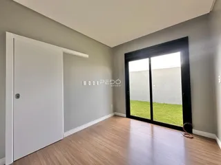 Sala de estar com piso de madeira e porta branca, com vista para o jardim.
