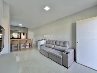 Sala de estar moderna com sofá cinza e piso claro.