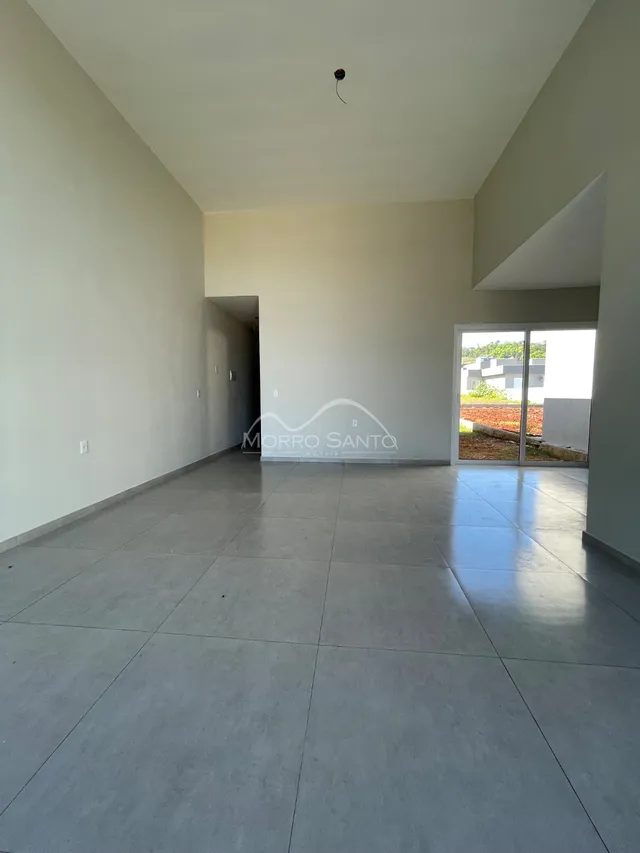 Vista de um ambiente interno amplo com piso de concreto polido e paredes brancas.