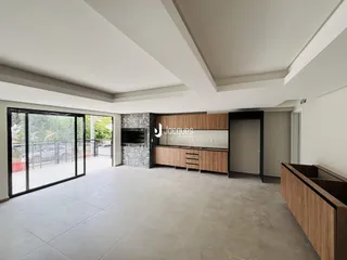 Ambiente interno de uma sala de estar com cozinha moderna e porta de vidro.