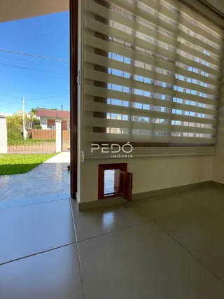 Vista interna de uma sala com persianas e porta de madeira.