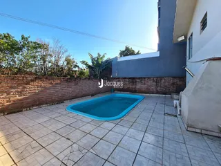 Área externa com piscina e muro de tijolos na propriedade.