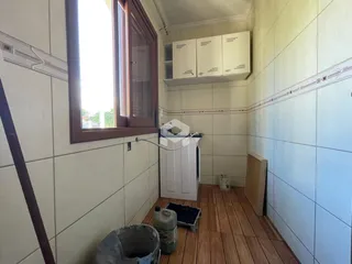 Interior de um cômodo com paredes de azulejo e piso de madeira.