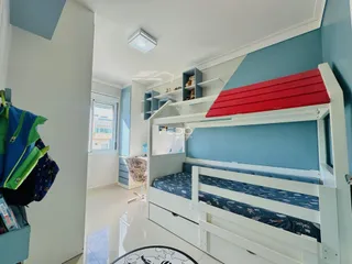 Quarto com estrutura de beliche e cama em um ambiente claro.