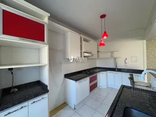 Cozinha com armários brancos e bancadas escuras.