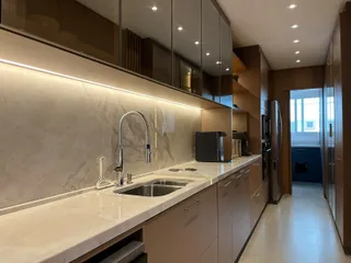 Uma cozinha moderna com bancada de mármore e armários escuros.