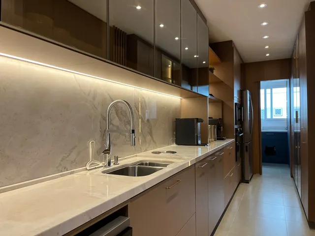 Uma cozinha moderna com bancada de mármore e armários escuros.