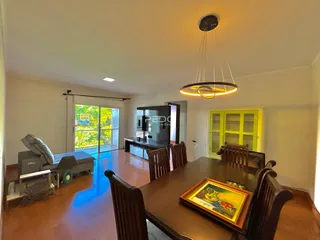 Sala de jantar com mesa de madeira e portas de vidro de acesso ao exterior.