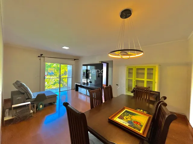 Sala de jantar com mesa de madeira e portas de vidro de acesso ao exterior.