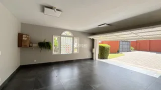 Uma sala de estar com piso escuro e janelas decorativas.