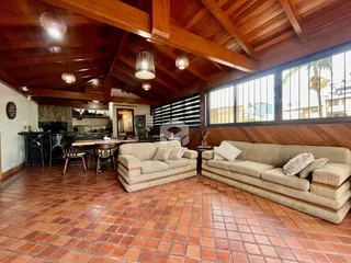 Sala de estar ampla com piso de tijolo vermelho e forro de madeira aparente.