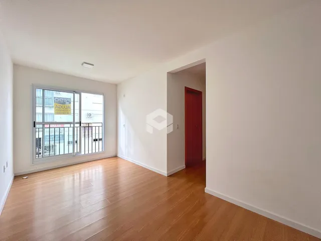 Ambiente interno com piso de madeira clara e parede branca.