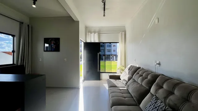 Sala de estar com sofá e grandes janelas que dão para o exterior.