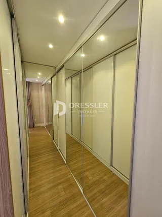 Corredor interno com piso de madeira e paredes espelhadas.