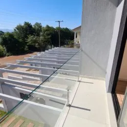 Varanda com grade de vidro mostrando a vista externa.
