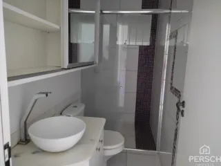 Banheiro com bancada, vaso sanitário e box de vidro transparente.