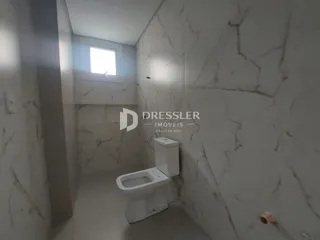 Corredor com paredes de mármore branco e vaso sanitário.