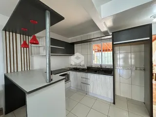 Vista interna de uma cozinha moderna com armários e revestimentos claros.