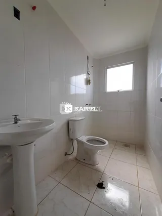 Foto interna de um banheiro com pia e vaso sanitário brancos.