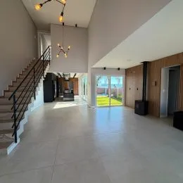 Hall de entrada com escadas e piso claro em ambiente interno.