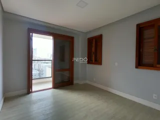 Ambiente interno de uma sala com porta de vidro abrindo para uma vista urbana.