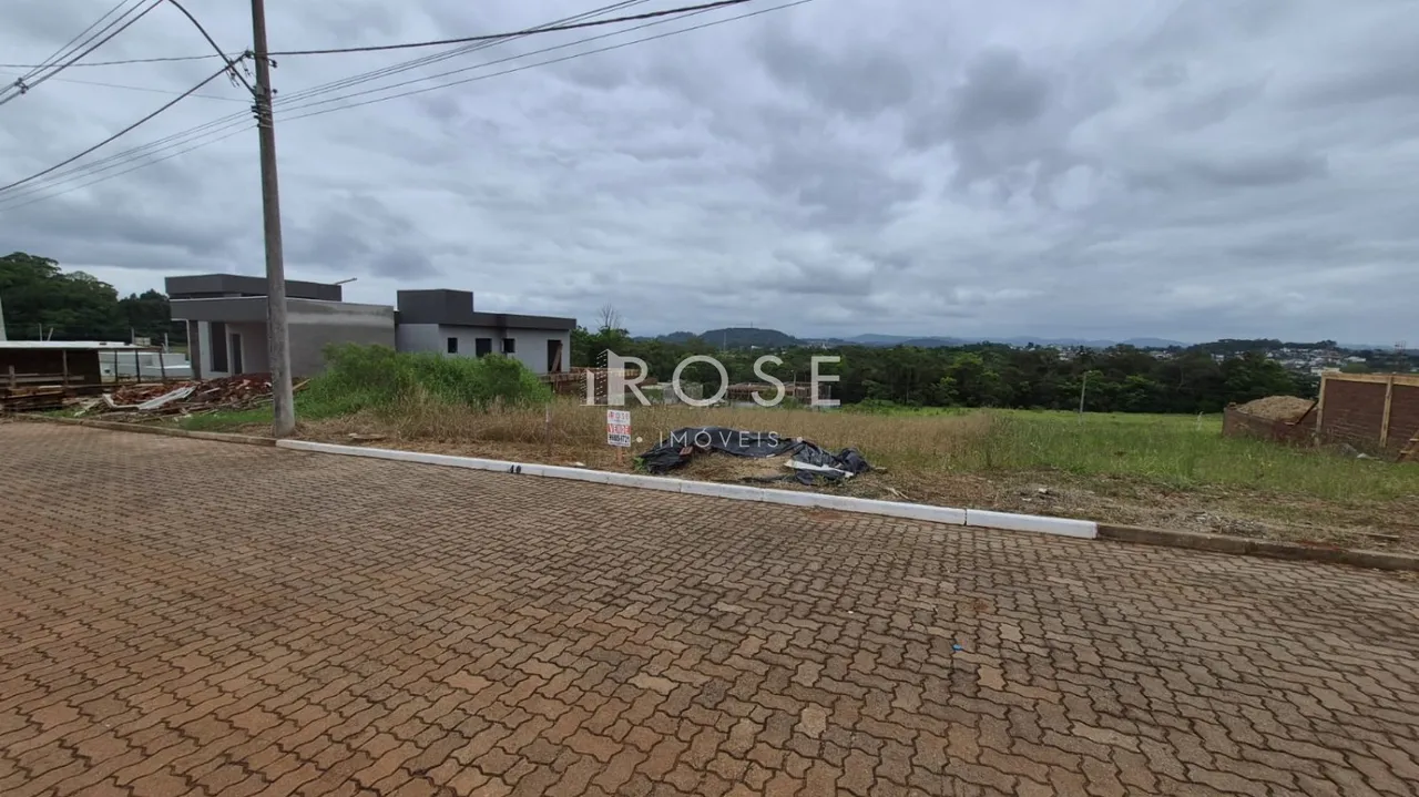 Vista externa de uma propriedade com terreno e construção ao fundo.
