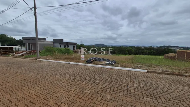 Vista externa de uma propriedade com terreno e construção ao fundo.