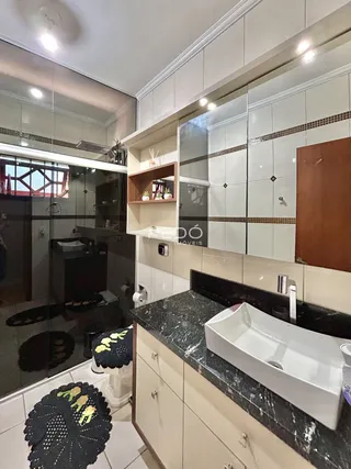 Foto de um banheiro moderno com revestimento branco e bancada escura.