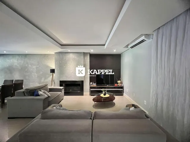 Sala de estar moderna com sofá grande e lareira em ambiente claro.