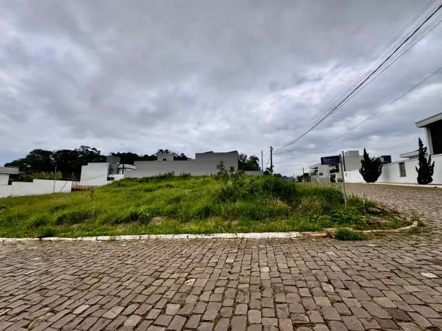 Vista externa de uma propriedade com paisagismo e edificações brancas em Lajeado.