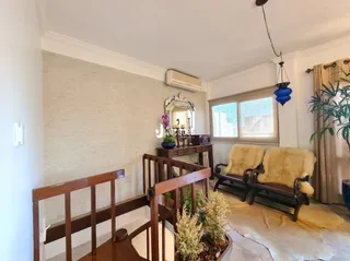 Uma sala de estar com detalhes em madeira e tapete claro.