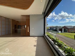 Vista interna de uma sala de estar com teto alto e grande abertura para o exterior.