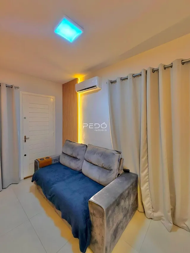 Sala de estar com sofá e cortinas brancas em um imóvel.