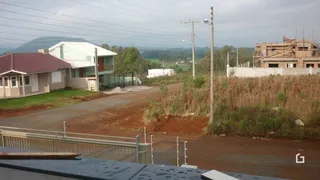 Vista externa da propriedade com área de terra e vegetação ao redor.