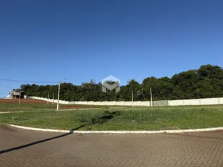Vista externa de uma propriedade com cerca e vegetação ao fundo.