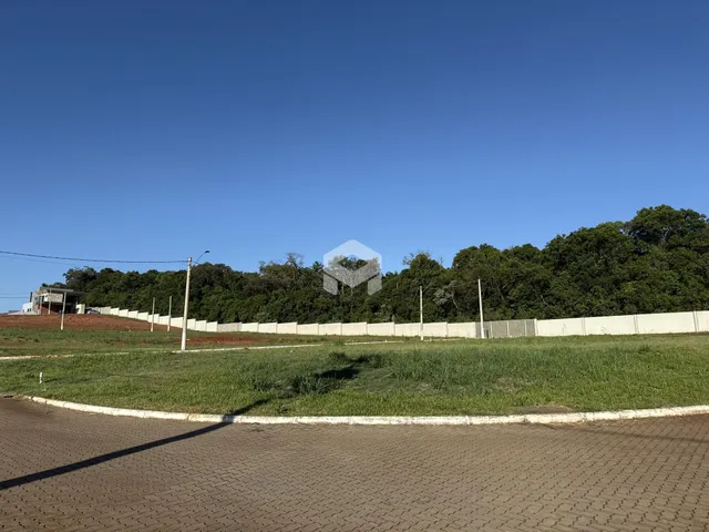 Vista externa de uma propriedade com cerca e vegetação ao fundo.