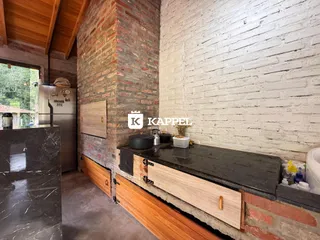 Cozinha com bancada escura e detalhes em tijolo aparente na área interna.