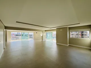 Ambiente amplo com piso claro e teto inclinado em uma residência.