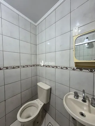 A foto mostra o interior de um banheiro com azulejos brancos.