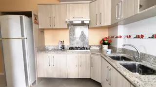 Cozinha moderna com armários de madeira clara e bancadas de granito.