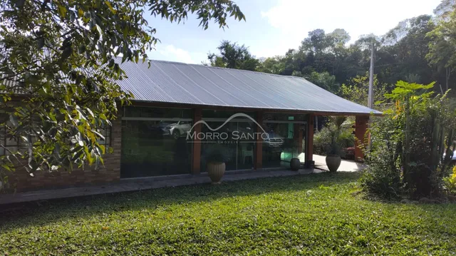Fachada de uma residência com telhado metálico e jardim verde.