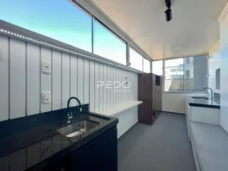 Vista interna de uma cozinha moderna com bancada escura e janelas amplas.