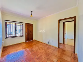 Sala de estar com piso de cerâmica terracota e porta de madeira em um imóvel no Brasil.