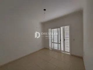 Vista interna de um cômodo com paredes brancas e piso claro.