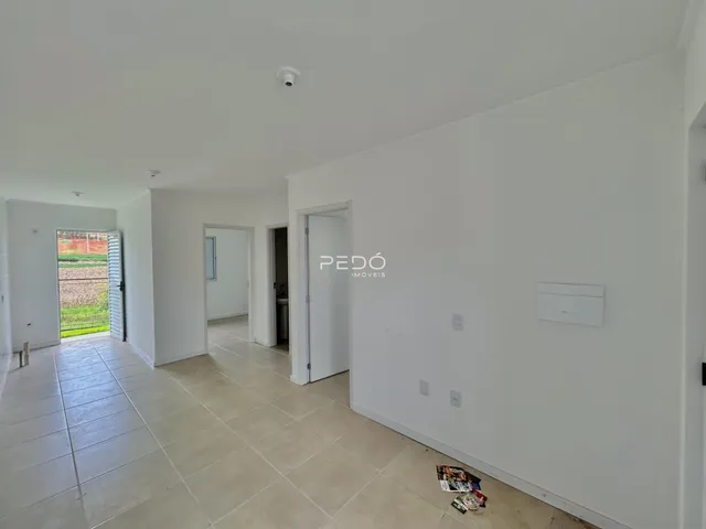 Hall de entrada com piso de cerâmica claro e paredes brancas.