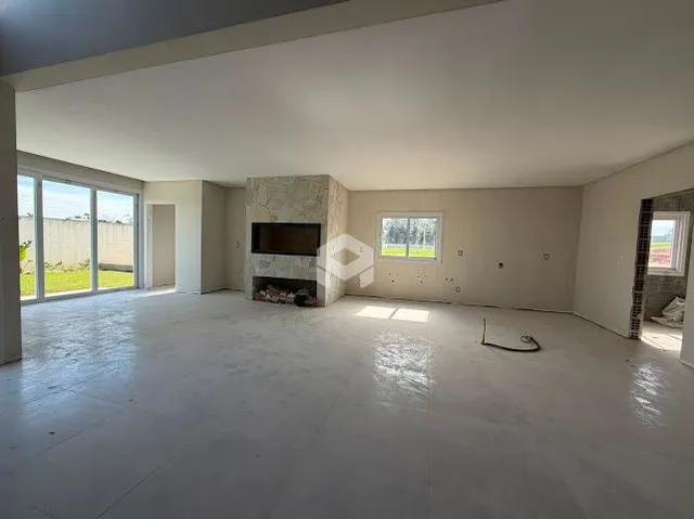 Espaço interno de uma residência com paredes brancas e piso de concreto.