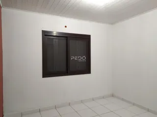 Parede branca com piso de cerâmica e uma estrutura de madeira escura na sala.