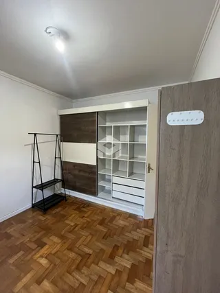 A sala apresenta piso de madeira e estantes embutidas.