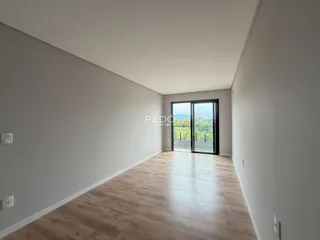 Ambiente interno de uma sala com piso de madeira clara e porta de vidro.